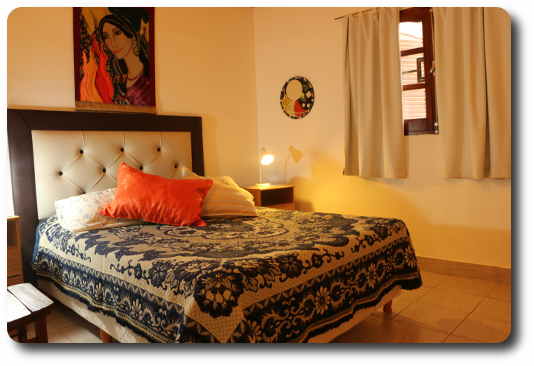 La fota muestra la habitación con cama doble decorada con artesenías de artistas del lugar del bunglow.